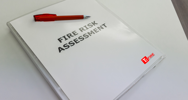 Fire Risk Assessment notepad on table with red pen and T2 Fire logo