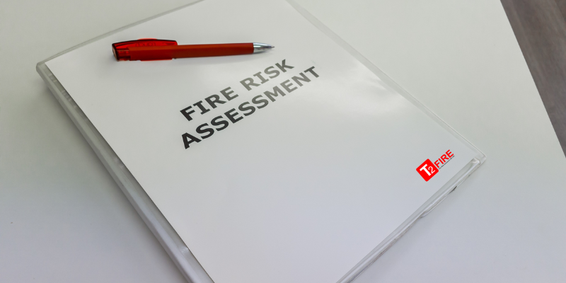 Fire Risk Assessment notepad on table with red pen and T2 Fire logo